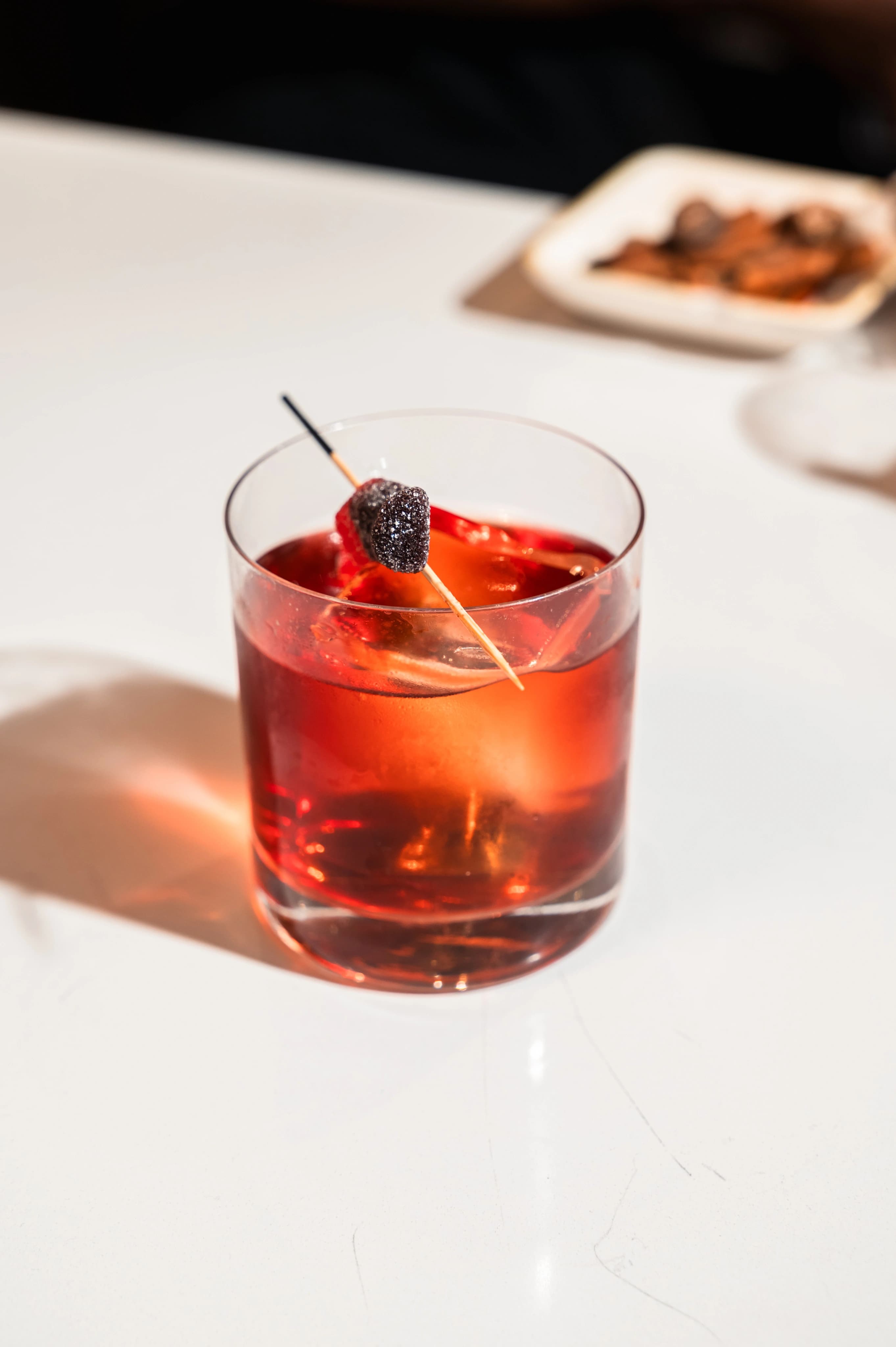 Dark red cocktail in a rocks glass with garnish