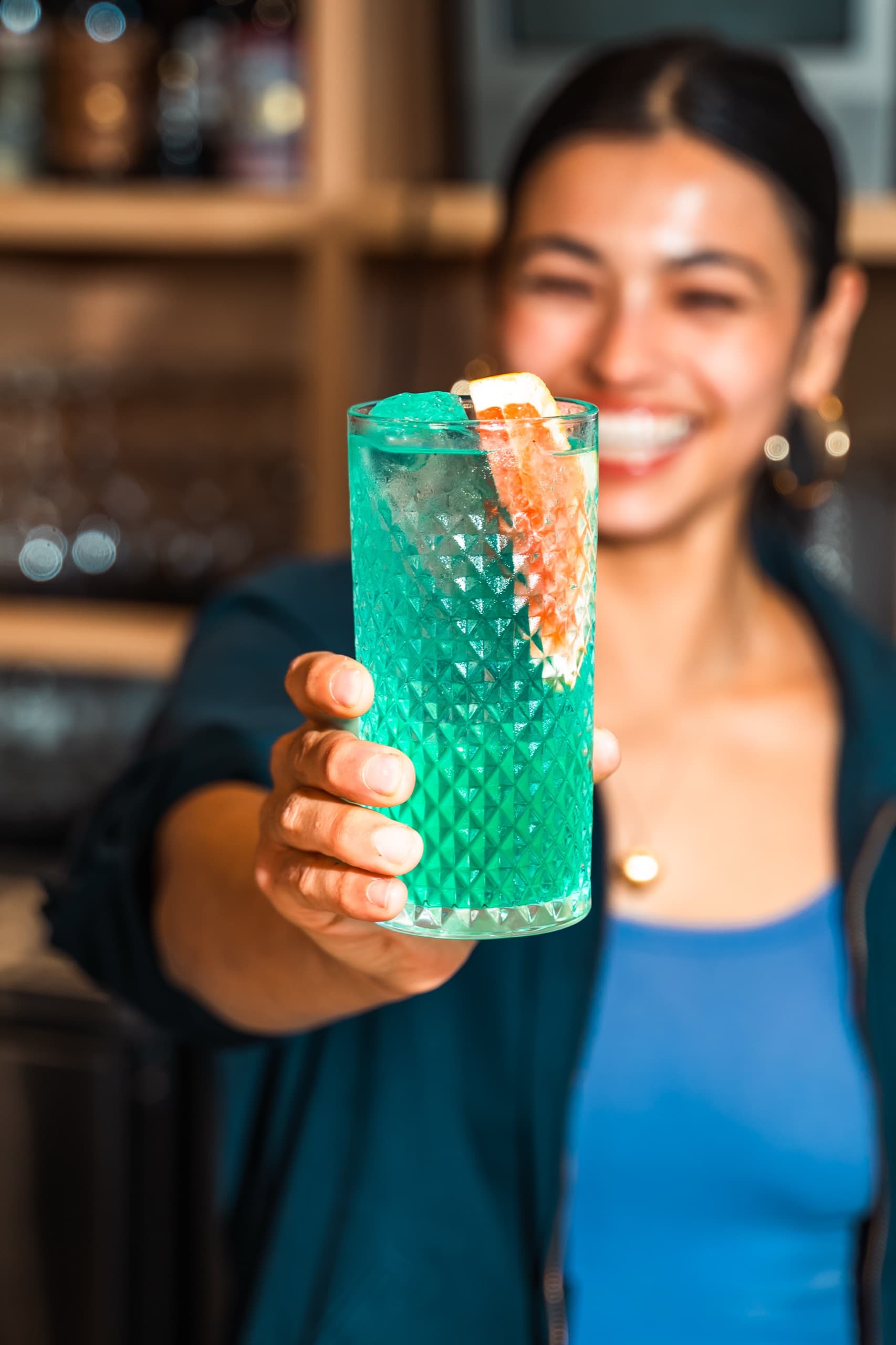 Guest holding a turquoise cocktail in a textured glass