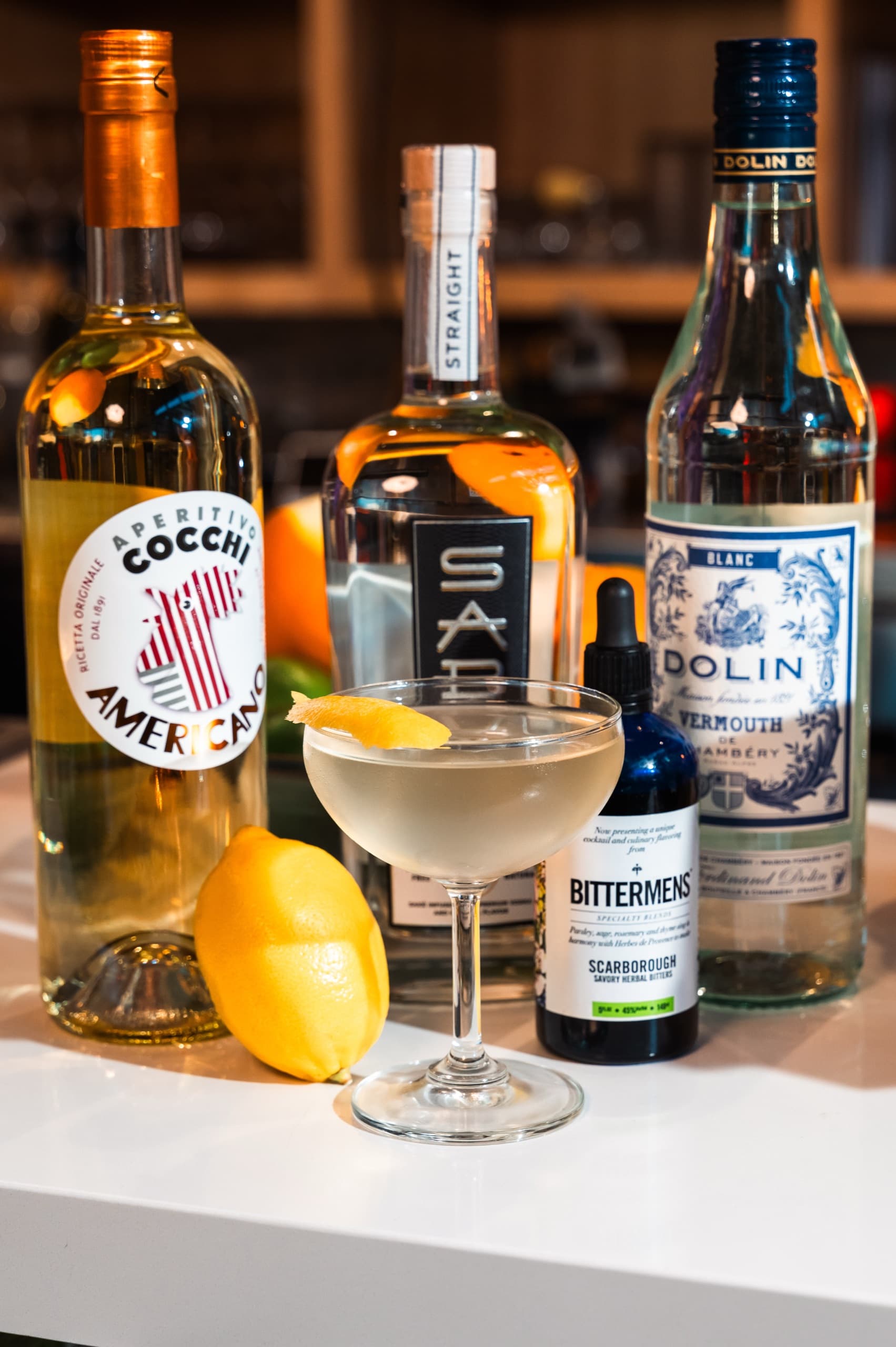 Bottles, lemon, and a coupe cocktail on the bar